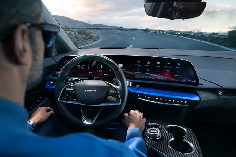 Front View of the 2026 OPTIQ-V Driving Through the Dusk Utilizing its Headlights | Cadillac of Mahwah in MAHWAH NJ